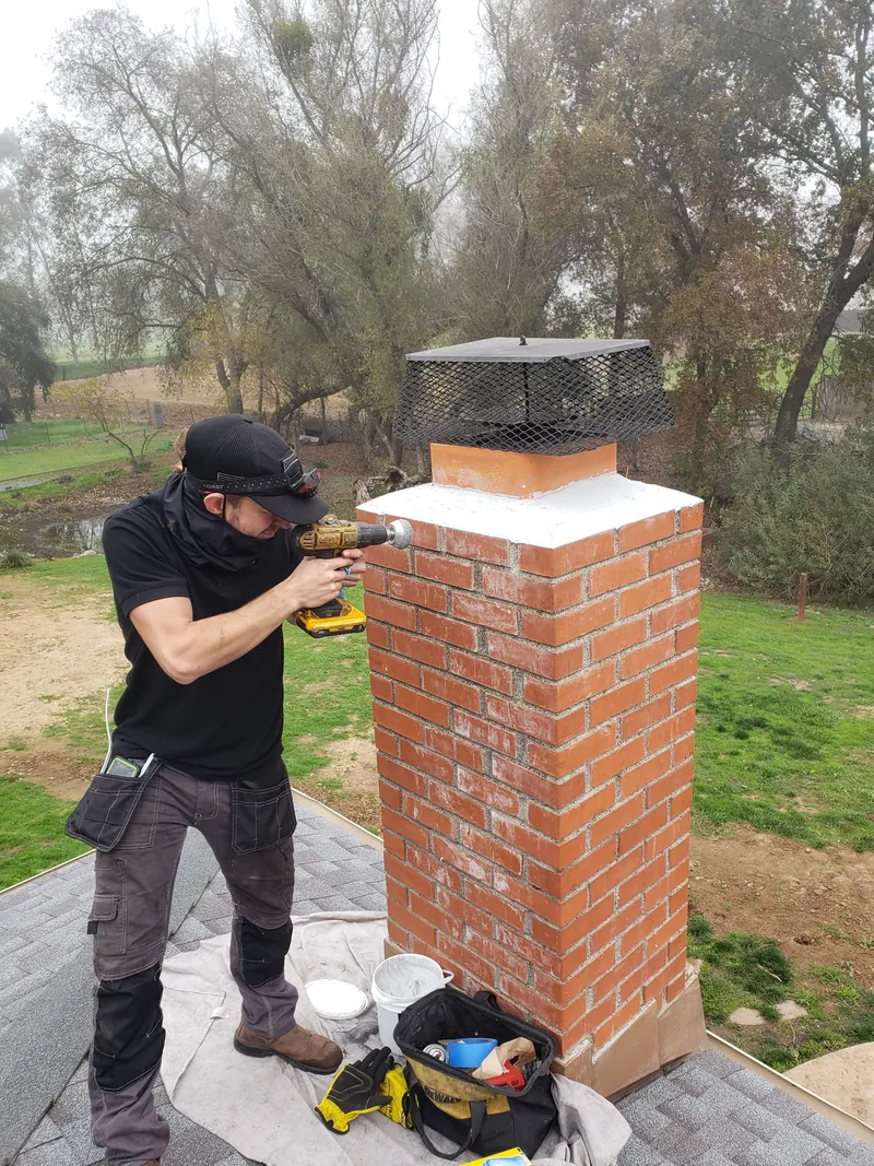 HexChimney technician sealing a chimney crown and fitting a chimney cap on an East Bay rooftop